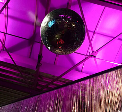 Club Link führt zu allen Einträgen der Kategorie "Club". Eine Discokugel hängt von einer lilafarbig angeleuchteten Decke.